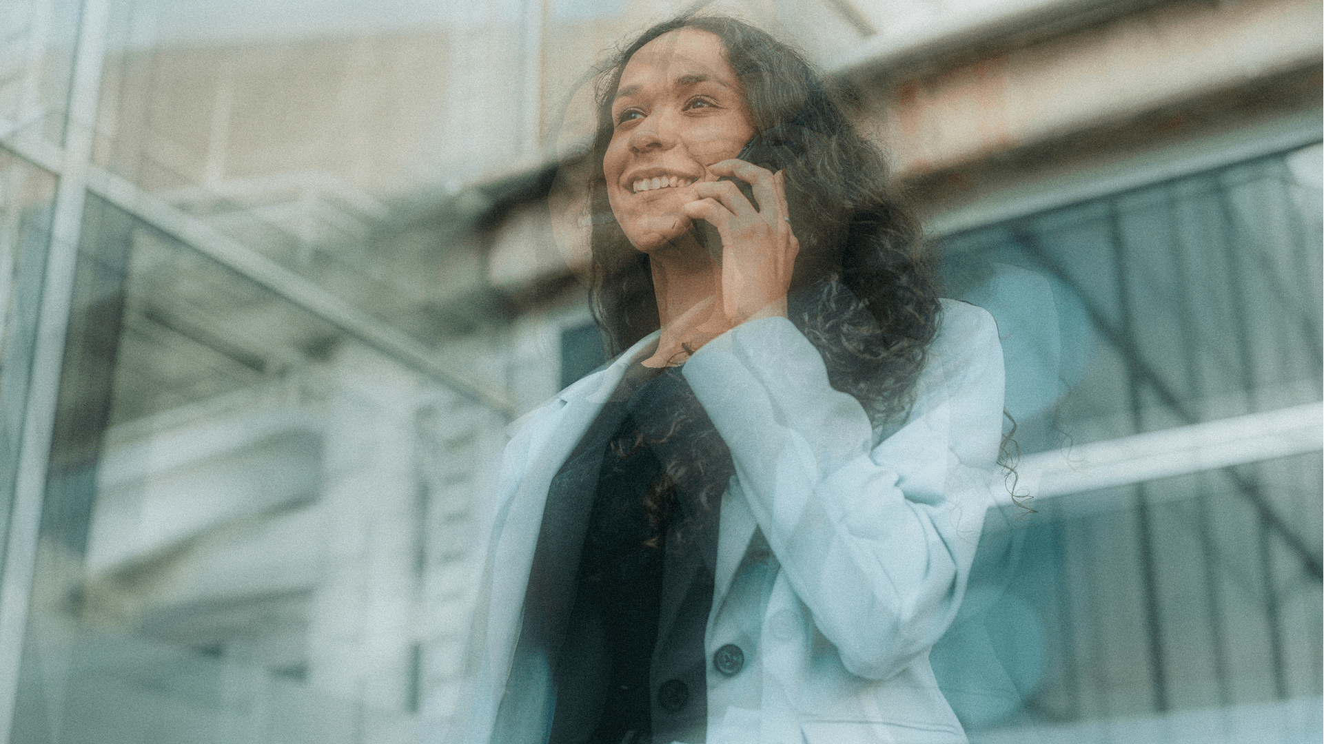Woman on phone in front of glass architecture